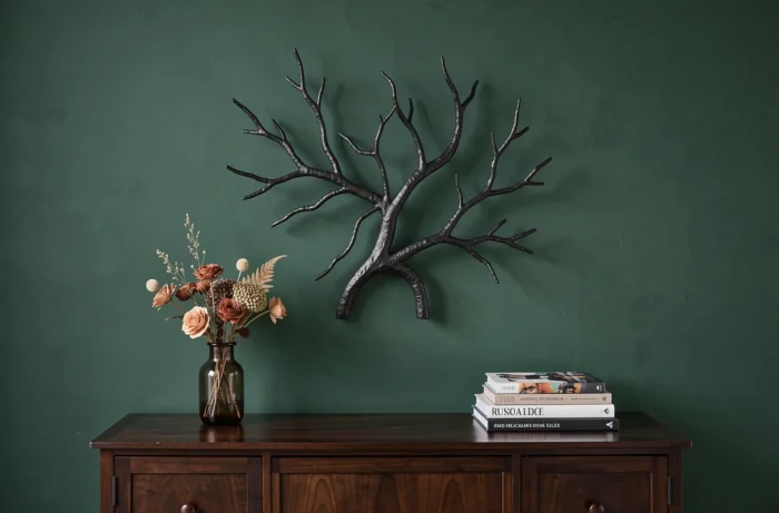 Applique murale sculpturale en fer forgé noir montée en décoration au-dessus d'un buffet espresso sur mur vert forêt