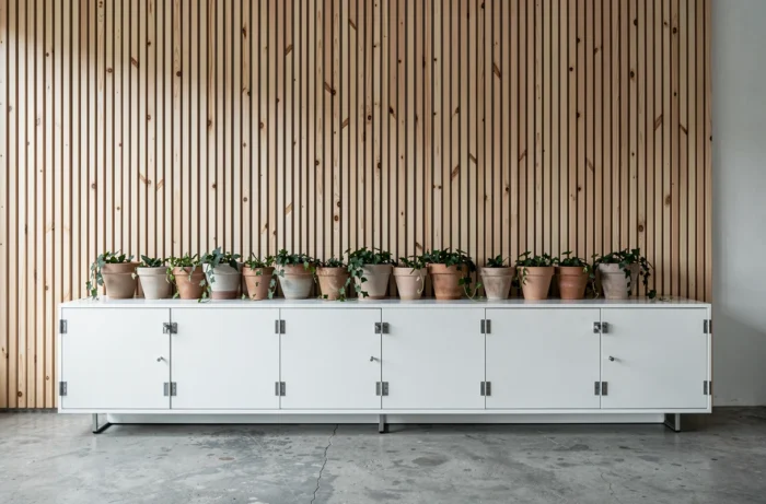 Panneau en tasseaux de bois verticaux en pin naturel au-dessus d'un buffet laqué blanc